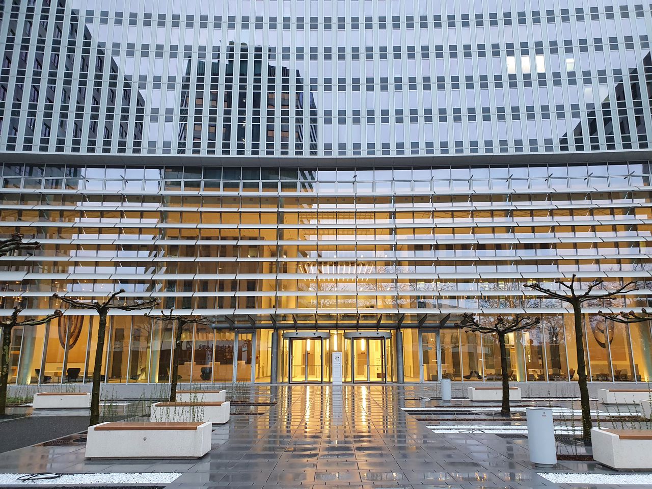 Mastering the First Impression: Your intriguing post title goes here Futuristic glass building with reflective facade and entrance illuminated at twilight.